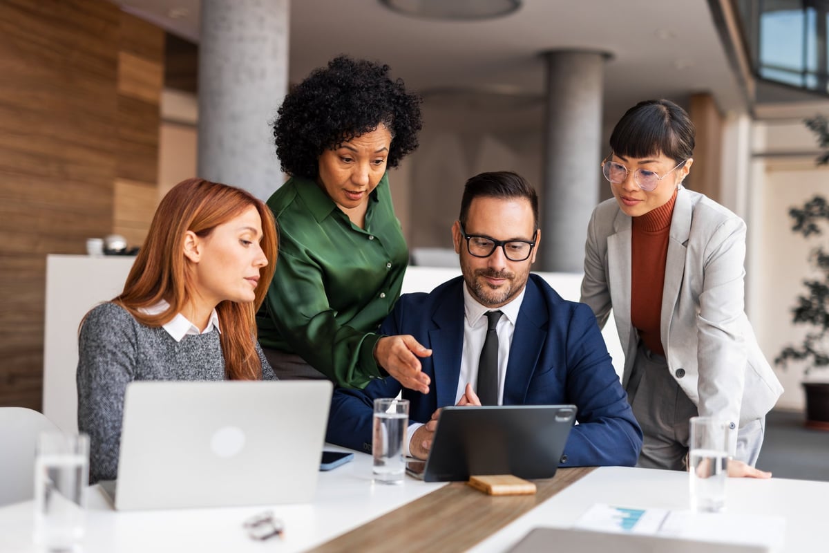 Diverse team of professionals collaborating with laptops in a modern office setting