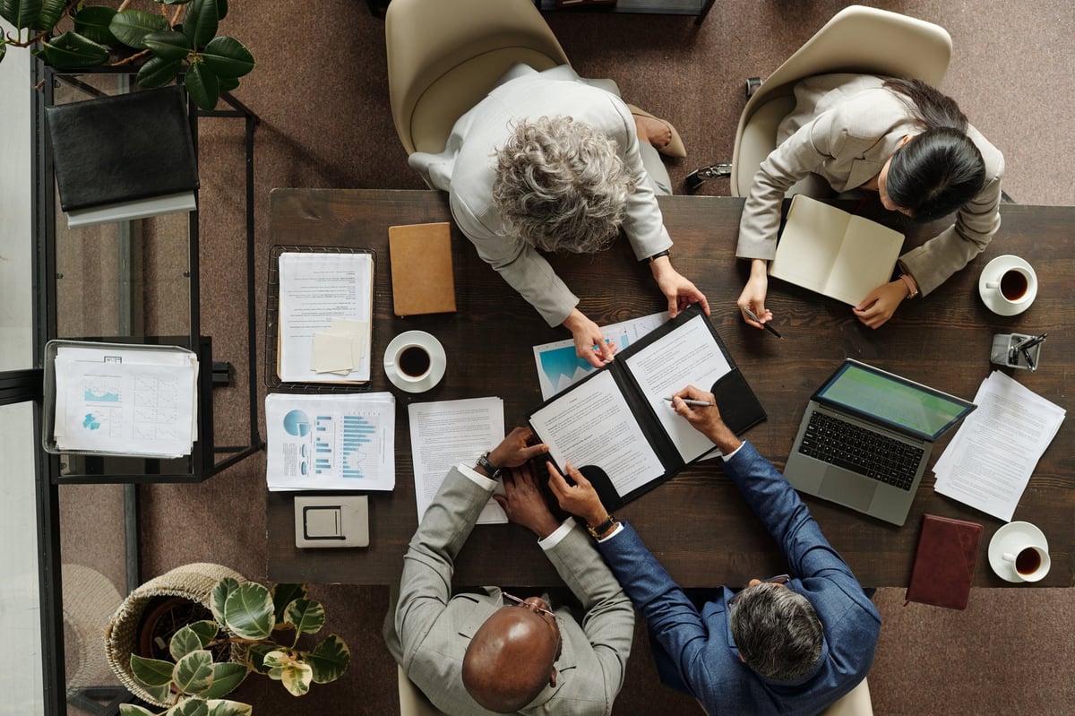Multiethnic business professionals collaborating around table with laptops and documents