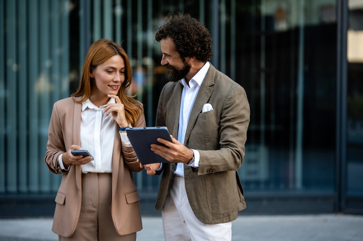 Business partners reviewing project details outside modern office building